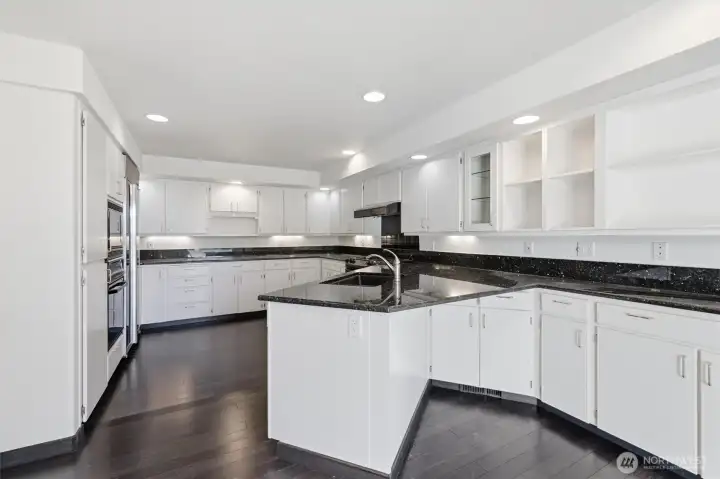 Spacious chef's kitchen featuring extensive cabinetry, granite countertops, stainless steel appliances, center island with prep sink, and abundant workspace for cooking and entertaining. Spacious chef's kitchen featuring extensive cabinetry, granite countertops, stainless steel appliances, center island with prep sink, and abundant workspace for cooking and entertaining.