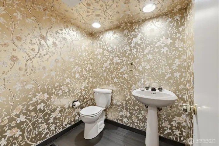 Elegant powder room featuring designer floral wallpaper, pedestal sink, and distinctive character that adds charm and personality to the home. Elegant powder room featuring designer floral wallpaper, pedestal sink, and distinctive character that adds charm and personality to the home.