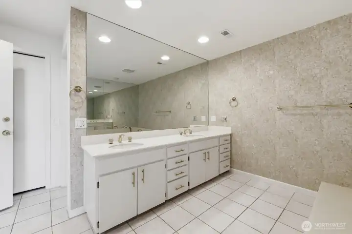 Spacious primary bath featuring dual vanities, expansive wall-to-wall mirrors, abundant storage, and generous countertop space. Spacious primary bath featuring dual vanities, expansive wall-to-wall mirrors, abundant storage, and generous countertop space.