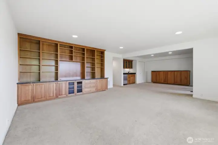 Expansive recreation room featuring custom built-in shelving, extensive storage, and flexible space for a media room, game room, home office, or entertaining area. Expansive recreation room featuring custom built-in shelving, extensive storage, and flexible space for a media room, game room, home office, or entertaining area.