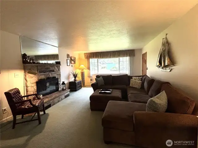 Comfortable living room with a fireplace. Large windows bath the room with light.