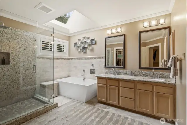 Primary bath with soaking tub, heated Travertine flooring and dual vanity