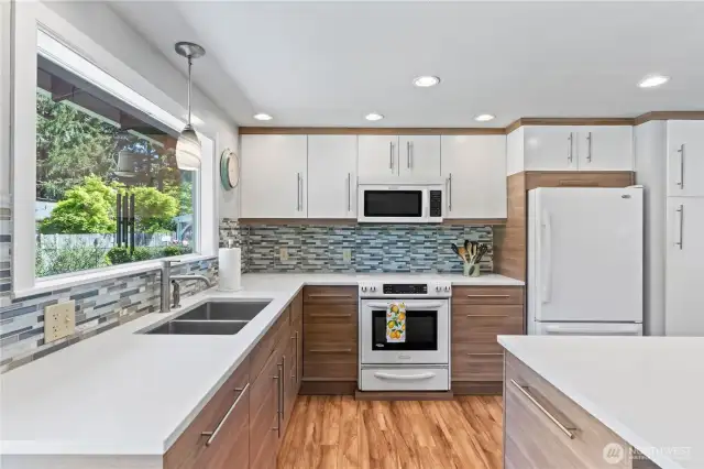Abundant natural light floods this thoughtfully designed kitchen, highlighting the dual-tone cabinetry, sleek hardware, and full tile backsplash.