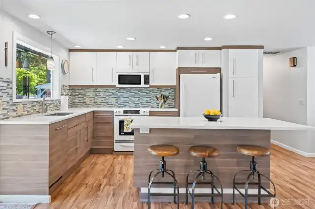 Modern chef’s kitchen with oversized quartz island, bar seating, pendant lighting, and custom cabinetry—blending functionality with style in every detail.