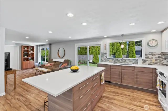 Stunning open-concept design featuring a fully remodeled kitchen with quartz countertops, designer tile backsplash, and ample cabinet space with soft-close drawers.