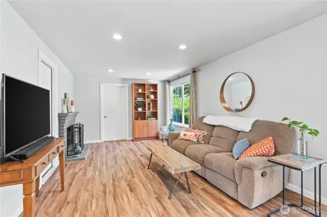 Experience comfort and charm in this inviting living room featuring a cozy wood-burning fireplace, large picture window for natural light, and warm laminate maple flooring. Perfectly situated off the kitchen, this flexible space is ideal for relaxing evenings or entertaining guests at 3727 Hoadly Loop SE in Tumwater.
