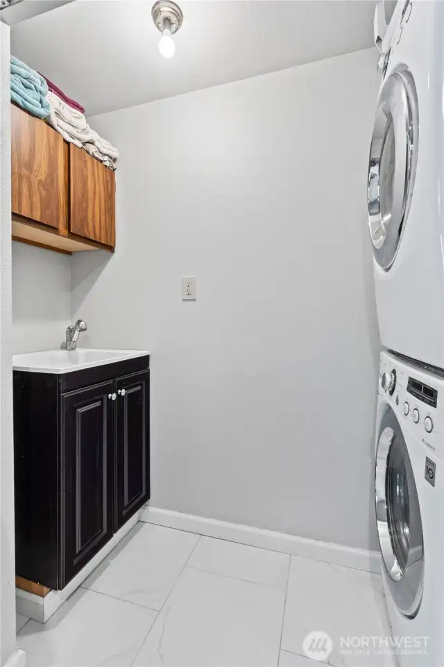 Enjoy a dedicated laundry room complete with a premium LG double stack washer and dryer, deep utility sink, upper storage cabinets, and ample walk-in space. This functional and private area offers convenience and organization, making household chores seamless.