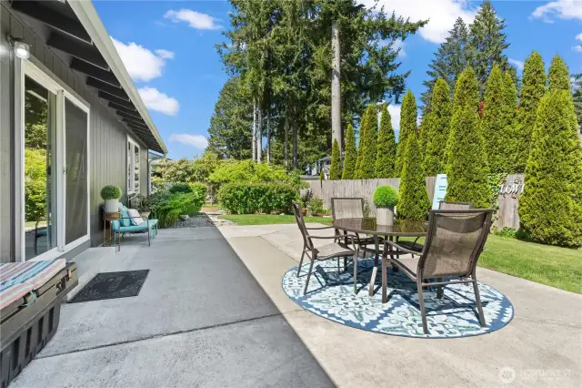 A closer look at the charming patio setup, complete with a shaded dining area and cozy seating space. This outdoor retreat is perfect for al fresco meals or winding down in the tranquility of your private backyard oasis.