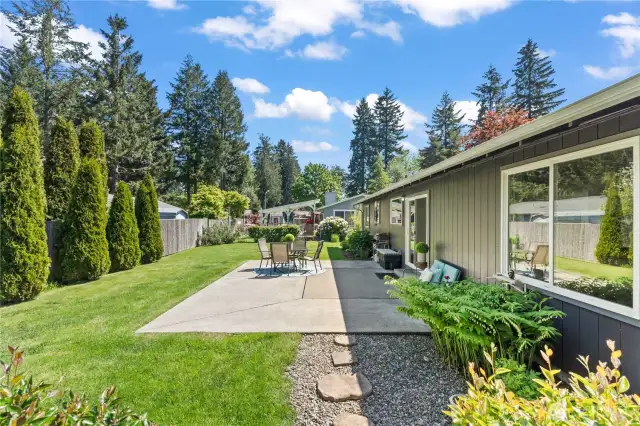Enjoy seamless indoor-outdoor living with this spacious concrete patio, surrounded by manicured garden beds and lush greenery. The large windows and sliding doors offer easy access and plenty of natural light, making this the perfect space for summer BBQs, lounging, and entertaining guests.