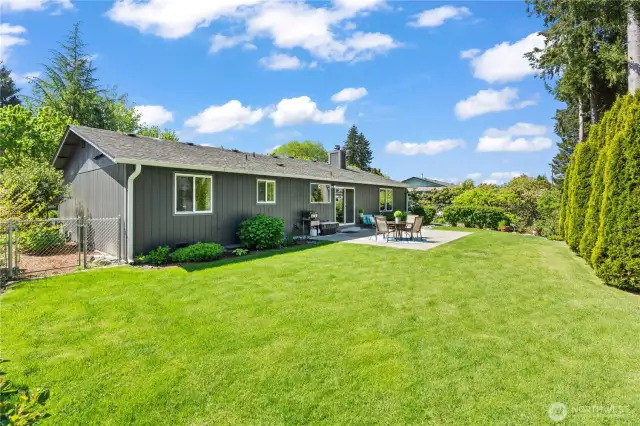 This spacious, sun-drenched backyard offers lush green lawn, privacy hedges, and a fully fenced layout—ideal for pets, gardening, or soaking up the Pacific Northwest summer. The large patio space is perfect for dining al fresco, weekend lounging, or entertaining guests in a peaceful, landscaped setting.