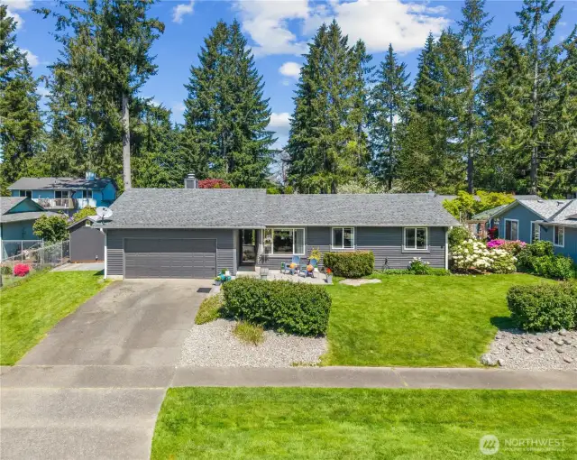 Welcoming front yard with a lush green lawn, decorative rock beds, and a cozy seating area—offering excellent curb appeal and neighborhood charm.