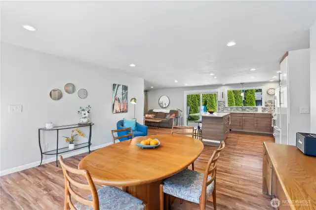 Enjoy seamless flow in this stunning open-concept living space. The remodeled interior features updated laminate maple flooring, recessed lighting, and an expansive view from the dining area into the cozy living room and gourmet kitchen. With quartz countertops, a custom island, and large windows letting in natural light, this space is perfect for entertaining and everyday living.