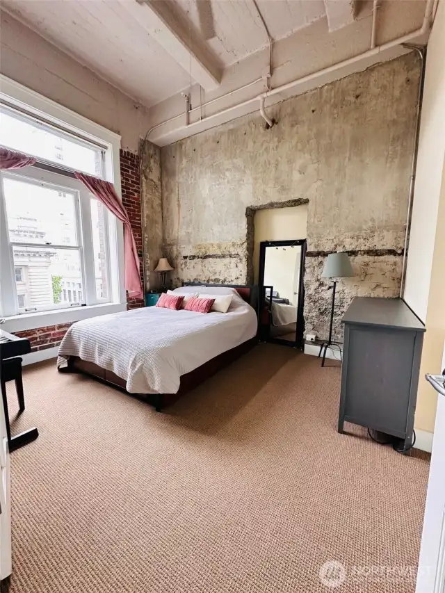 Bedroom with stone walls and soring ceilings