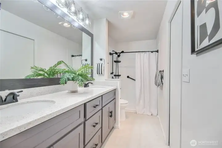 The primary bathroom offers double sinks with granite countertops and a walk-in shower, complemented by ample cabinet storage.