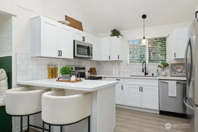 Beautiful quartz countertops on breakfast bar, white cabinets & SS appliances in kitchen. Nice!