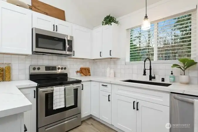 Another view of kitchen with range, microwave, deep kitchen sink, dishwasher.
