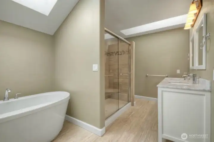 Primary bath with soaking tub, skylight, and double vanity