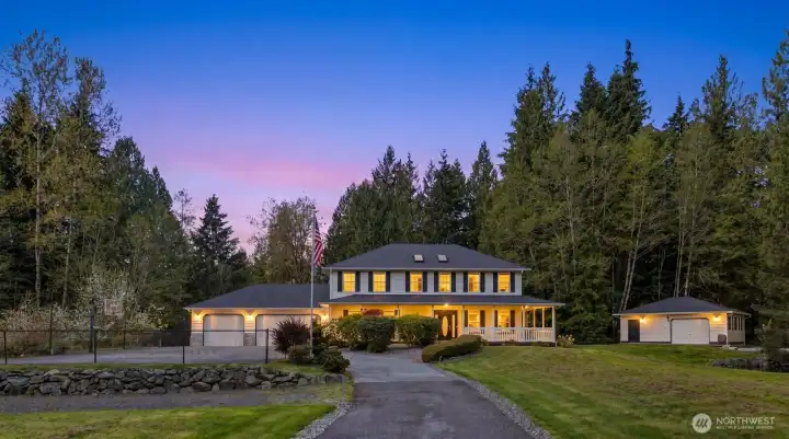 Welcome to this stunning countryside estate, beautifully illuminated against a twilight sky and nestled among mature trees.