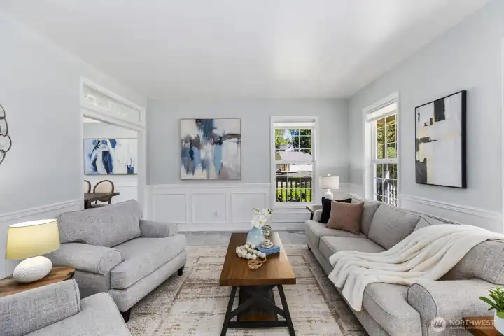 Relax in the sun-drenched formal living room, showcasing beautiful hardwood floors and custom wainscoting details throughout.