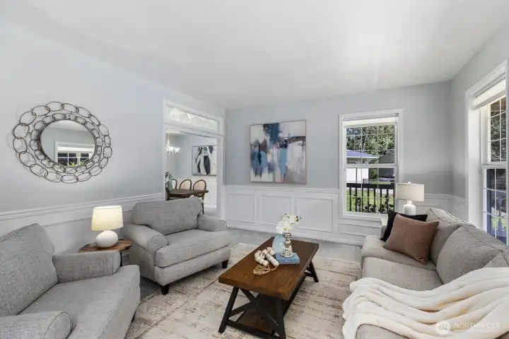 This elegant living space features sophisticated wainscoting, fully wood-wrapped windows, and expansive windows that flood the room with natural light.