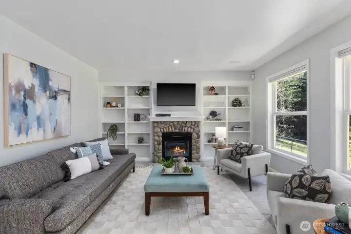 The inviting family room is centered around a cozy fireplace with river rock surround and flanked by beautiful custom built-in shelving.