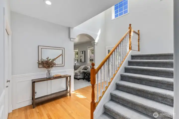 A beautifully crafted staircase with classic wainscoting and warm wood accents leads you to the upper level of the home.