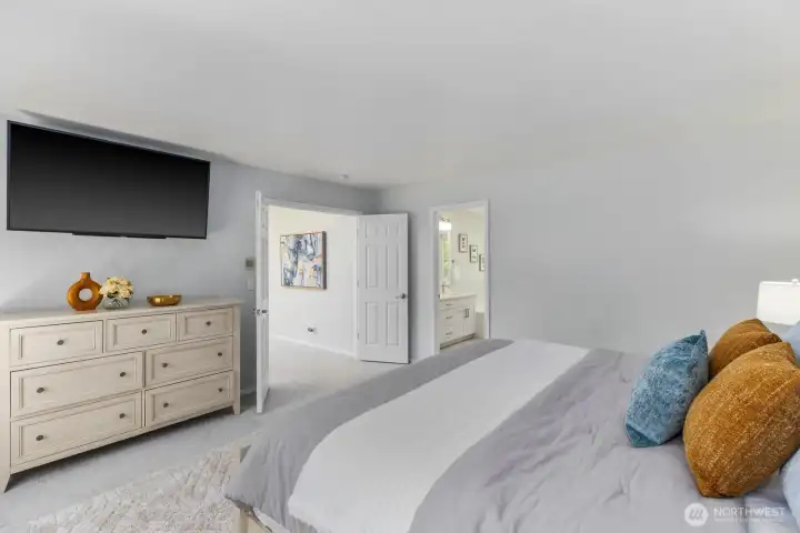 This comfortable bedroom serves as a peaceful retreat, featuring plush carpeting and generous natural light.