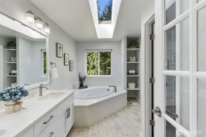 Step into the luxurious, spa-like primary en-suite boasting a dual-sink vanity and a relaxing soaking tub situated perfectly beneath a skylight.