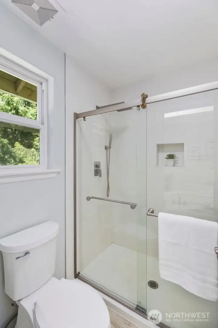 The primary en-suite is completed by a sleek, glass-enclosed walk-in shower featuring contemporary tilework.