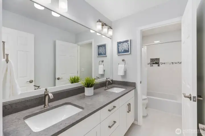 This beautifully finished upper-level bath includes dual sinks, modern lighting, and a separate room for the shower and toilet.