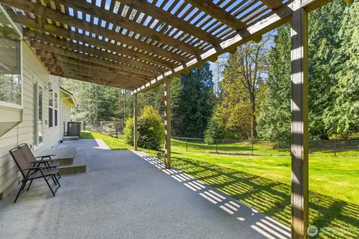 Step outside to an incredible outdoor living space featuring an expansive patio shaded by a stunning custom wooden pergola.
