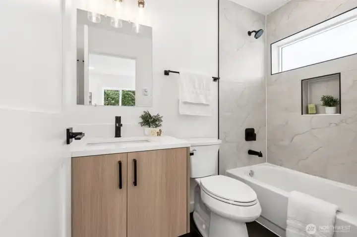 Upgraded bathroom with quartz countertops and beautiful tile surround.