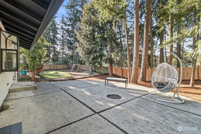 A spacious concrete patio featuring a built-in firepit and wood-burning area, perfect for parties and gatherings