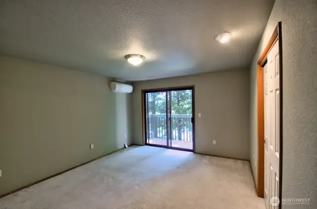 View of primary bedroom from doorway. Sliders lead to a deck overlooking the back yard and the lake.