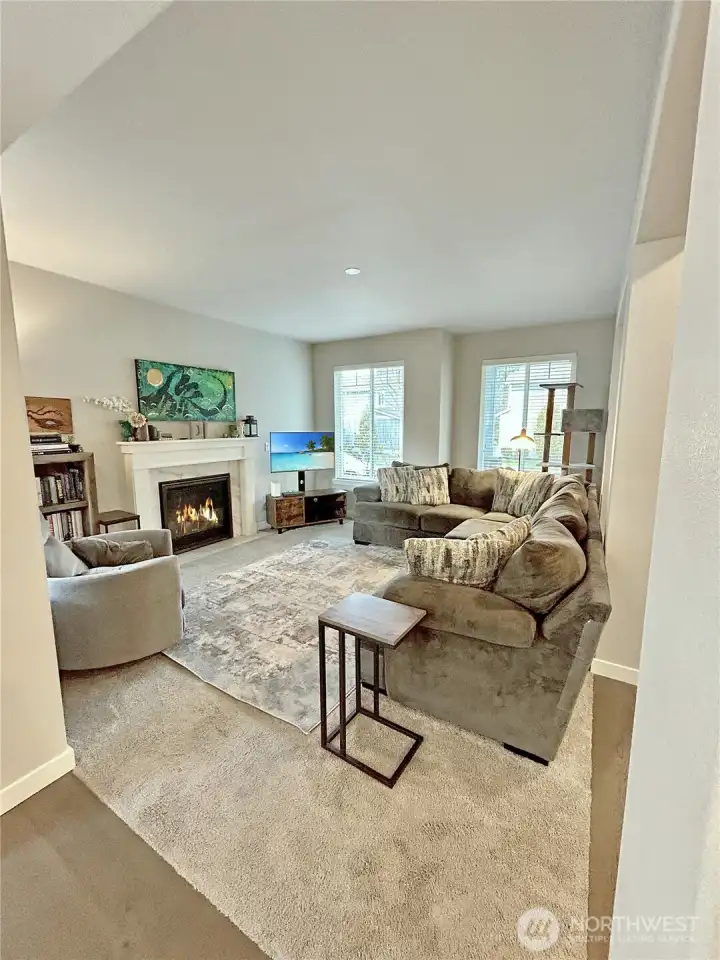Ample living room with gas fireplace is open to entry, dining and kitchen.