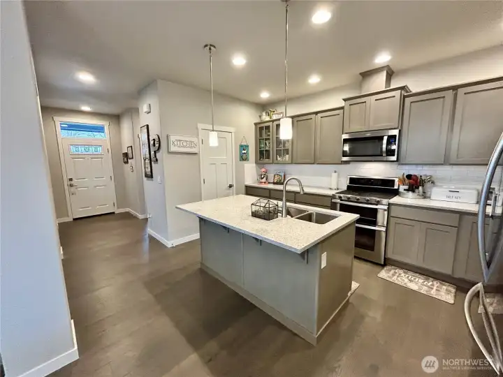 Stunning kitchen with walk-in pantry, beautiful, engineered hardwood floors, stained cabinets, quartz countertops and stainless appliances (all included), gas cooktop and double overs. Island offers seating as well.