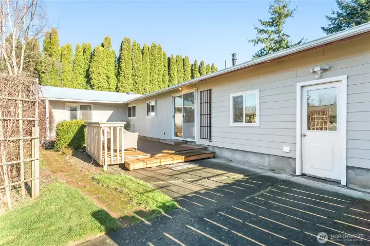 Garden path leads to apple trees, garden boxes. Garage door entry on right. Sliding door leads to kitchen.