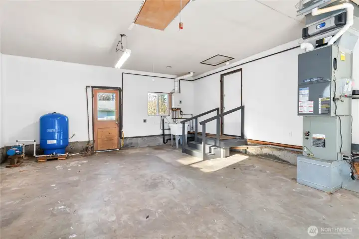 Garage attached to house with new well tank, on -demand hot water, new utility sink, natural gas furnace and workbench.