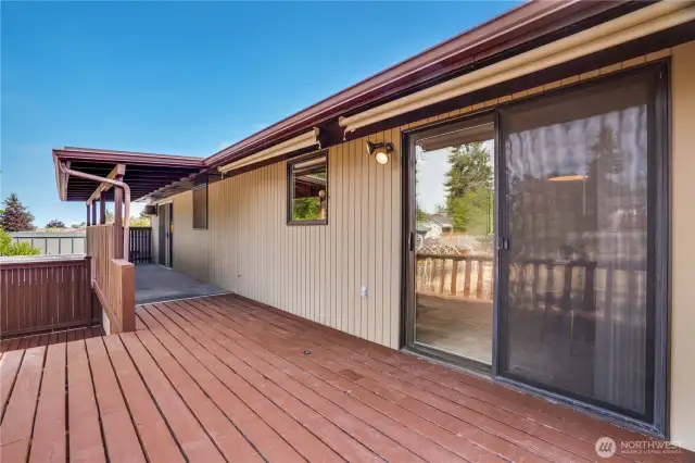 The deck extends from the kitchen to the primary suite. Stairs lead down to a lower platform and give easy access to the fenced back yard.