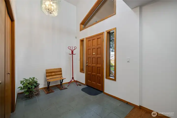 Inviting entry with soaring ceilings, warm wood accents, and abundant natural light creates an immediate sense of openness. Thoughtfully designed with clean lines and a welcoming feel, setting the tone for the home’s architectural style.