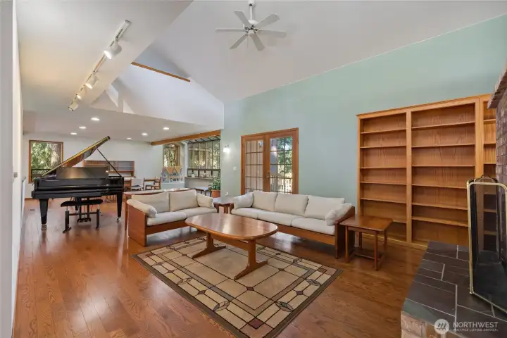 Open-concept living area with vaulted ceilings, rich hardwood floors, and abundant natural light creating a warm, inviting atmosphere.