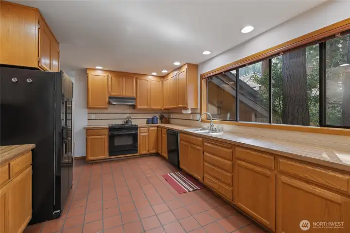 Open layout connecting kitchen, dining, and living areas beneath a loft overlook, enhancing flow, functionality, and architectural appeal.