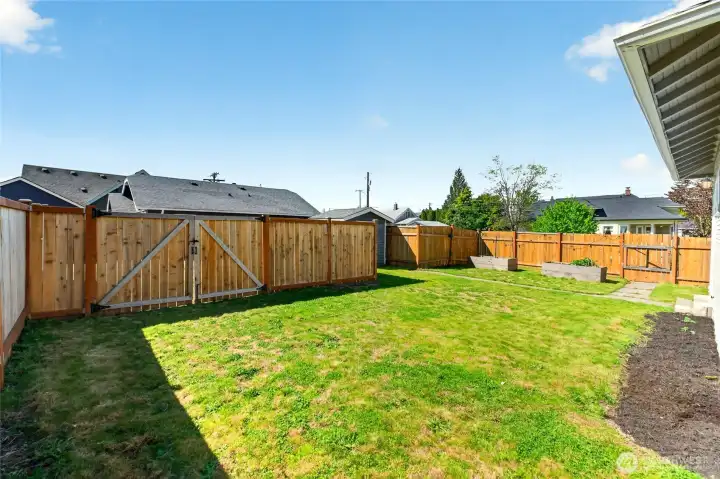 Fully fenced backyard with raised garden beds and Shed.