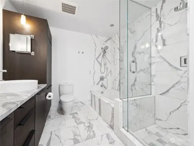 A serene soaking tub and a separate marble-tiled shower, all part of the opulent ensuite.