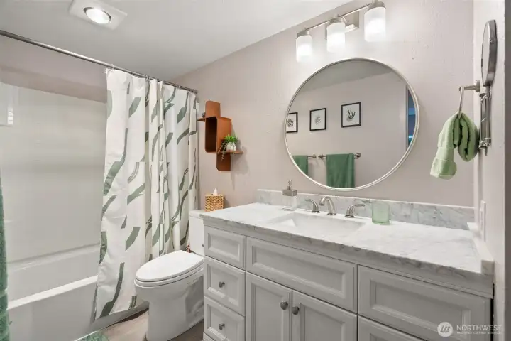 Updated bath includes marble top vanity, mirrors and modern lighting.