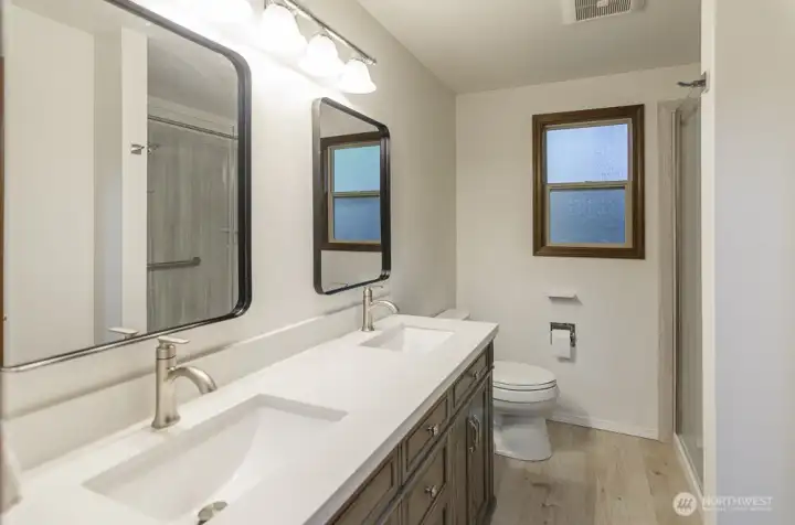 Recent updated primary bath has new vanity with double sinks new solid surface expanded walk-in shower, new flooring and decorative mirrors.
