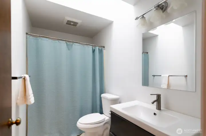 Hall full bath has tub/shower and updated vanity, flooring and mirror.