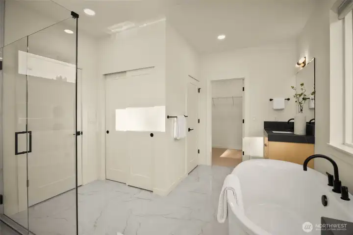 A chic spa-inspired luxurious bathroom, which includes a large glass-enclosed walk-in shower, and soaking tub.