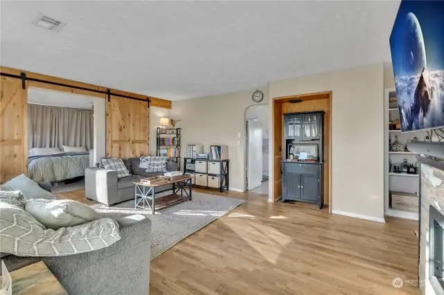 Spacious living room with hardwood floors and a gas fireplace to the right to keep you warm. The double barn doors on the left lead to the primary bedroom. The natural light greets you in the morning!