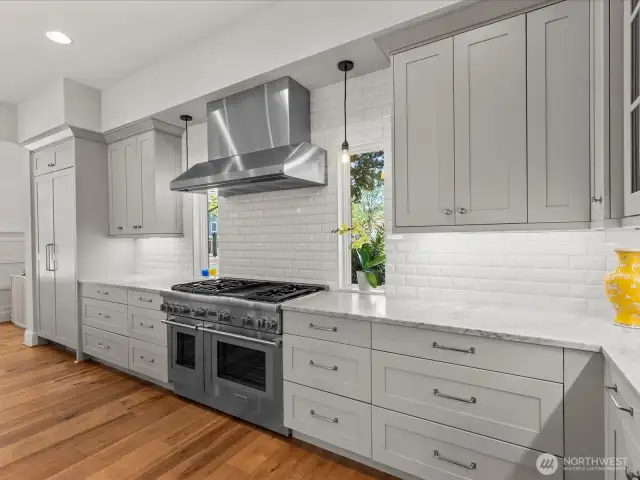 A built-in Thermador refrigerator, 6-burner gas stove, and commercial-grade hood blend seamlessly with sleek marble countertops and a custom tiled backsplash—creating a sophisticated culinary space that's as functional as it is beautiful.